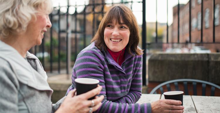 Women sat down at a table drinking coffee and chatting
