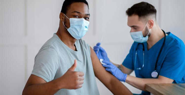 Black male with thumb up being vaccinated