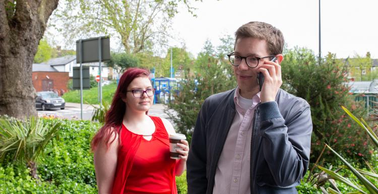 Man on the phone outside, standing next to a woman
