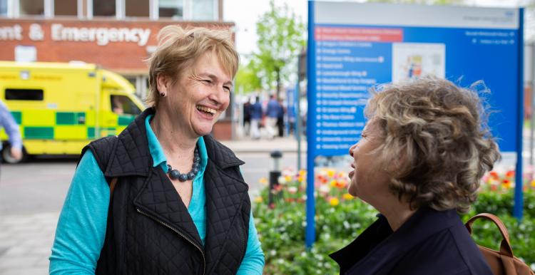 Two women speaking to one another outside a hospital