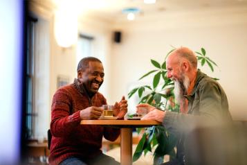 Two men sitting at a table talking and laughing