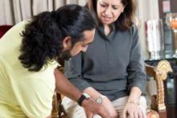 Physiotherapist helping an adult Asian woman sitting in a chair exercise her leg