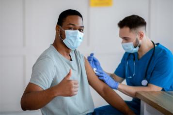 Black male with thumb up being vaccinated
