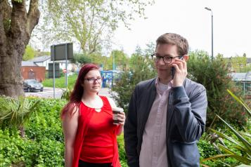 Man on the phone outside, standing next to a woman