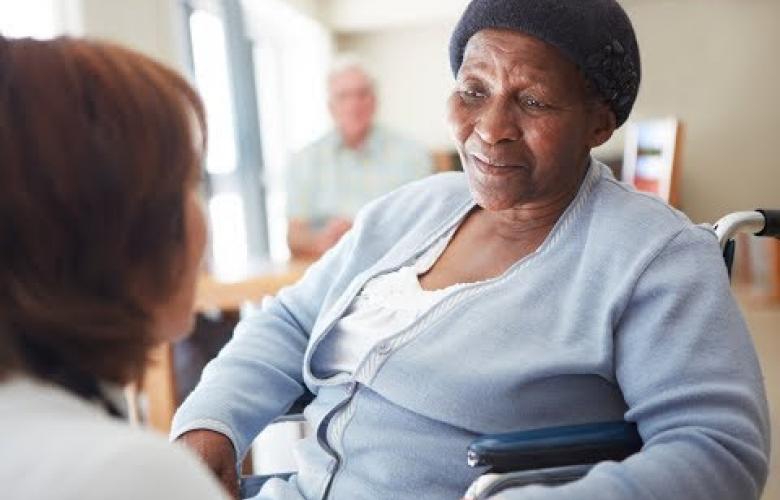 Black elderly woman ina nursing home being spoken to by a nurse