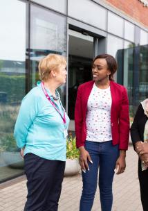 Three women standing outside a hospital talking Three women standing outside a hospital talking