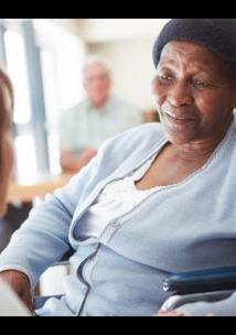 Black elderly woman ina nursing home being spoken to by a nurse
